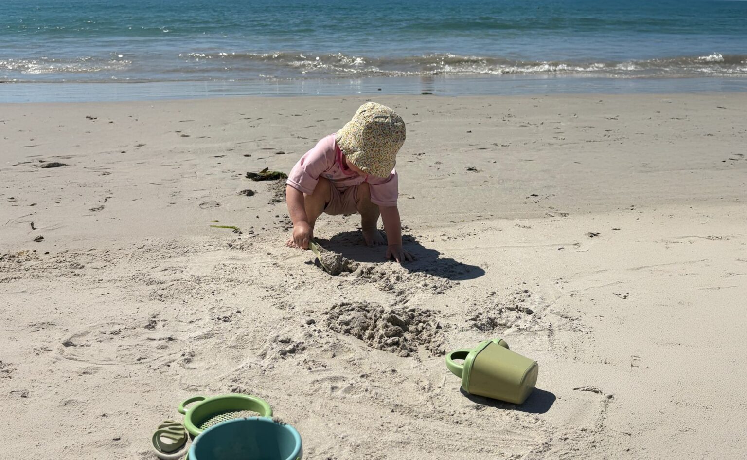 Kleine Lilli spielt barfuß am Strand